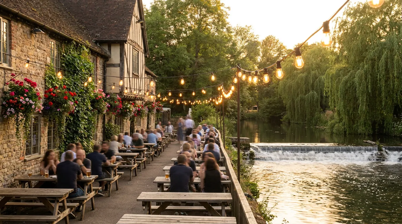 A riverside pub garden with warm bistro lights on a summer evening