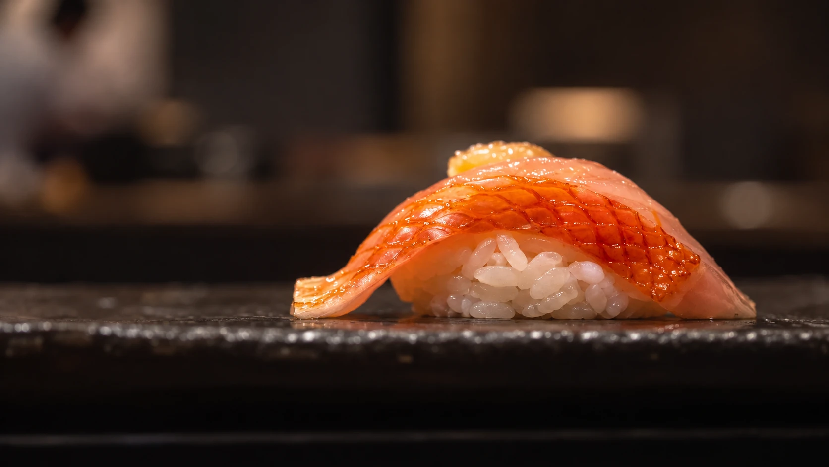 A piece of nigiri on a dark ceramic plate at Craft Omakase