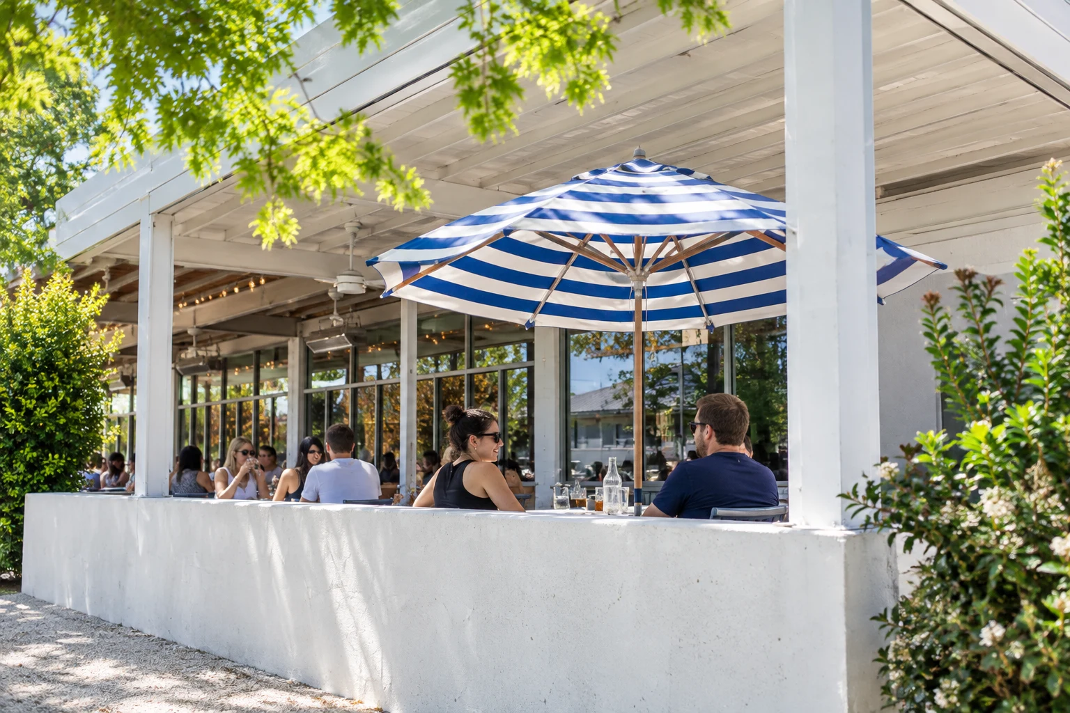 Striped umbrella above Launderette’s white patio enclosure