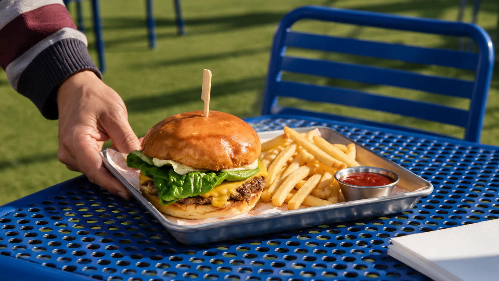 Cheeseburger and fries on a blue rooftop table at Rooftop Bar