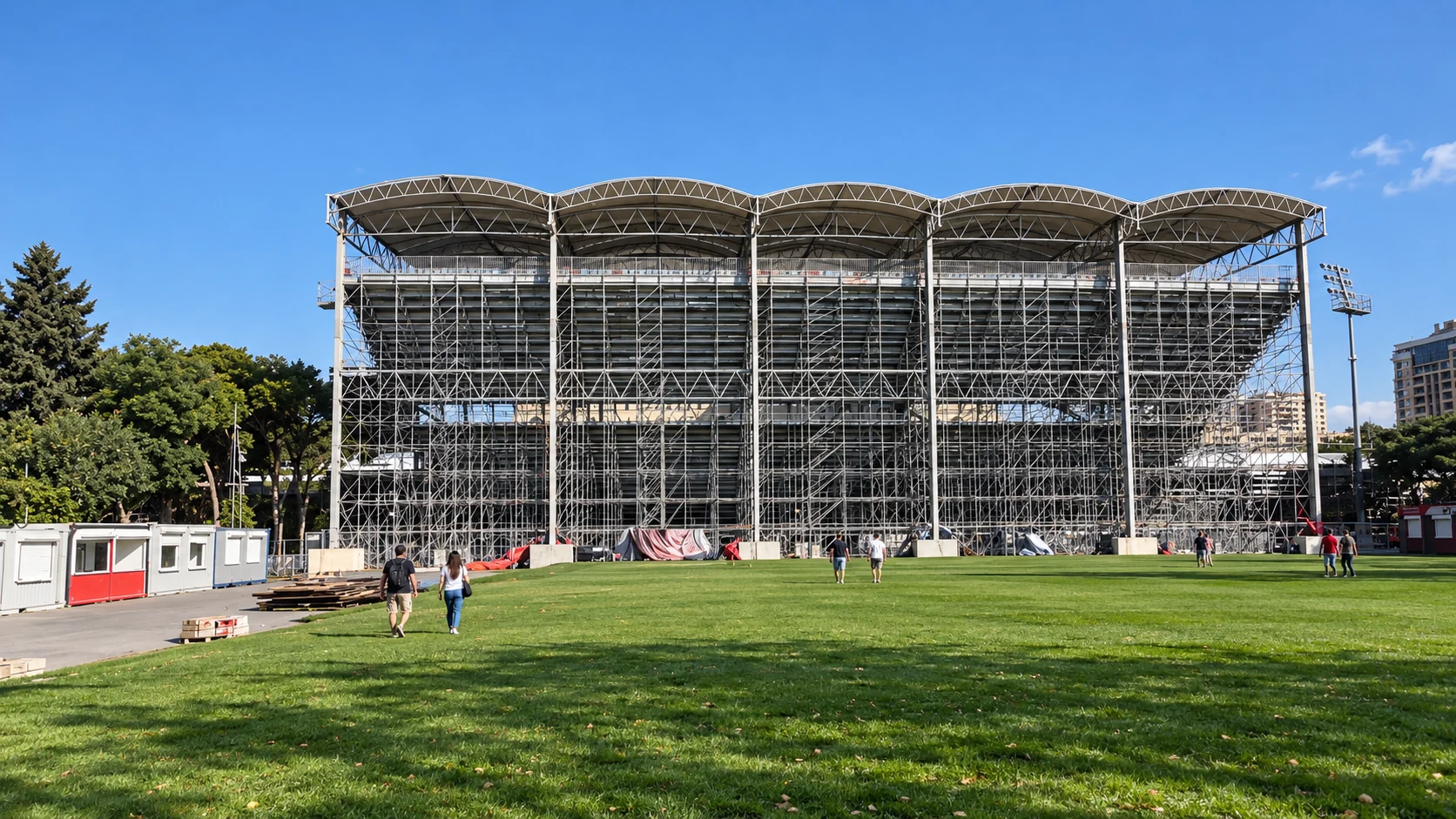 Exposed steel supports and the curved roof of the Absheron grandstand rise above the lawn behind Baku City Circuit’s main straight.