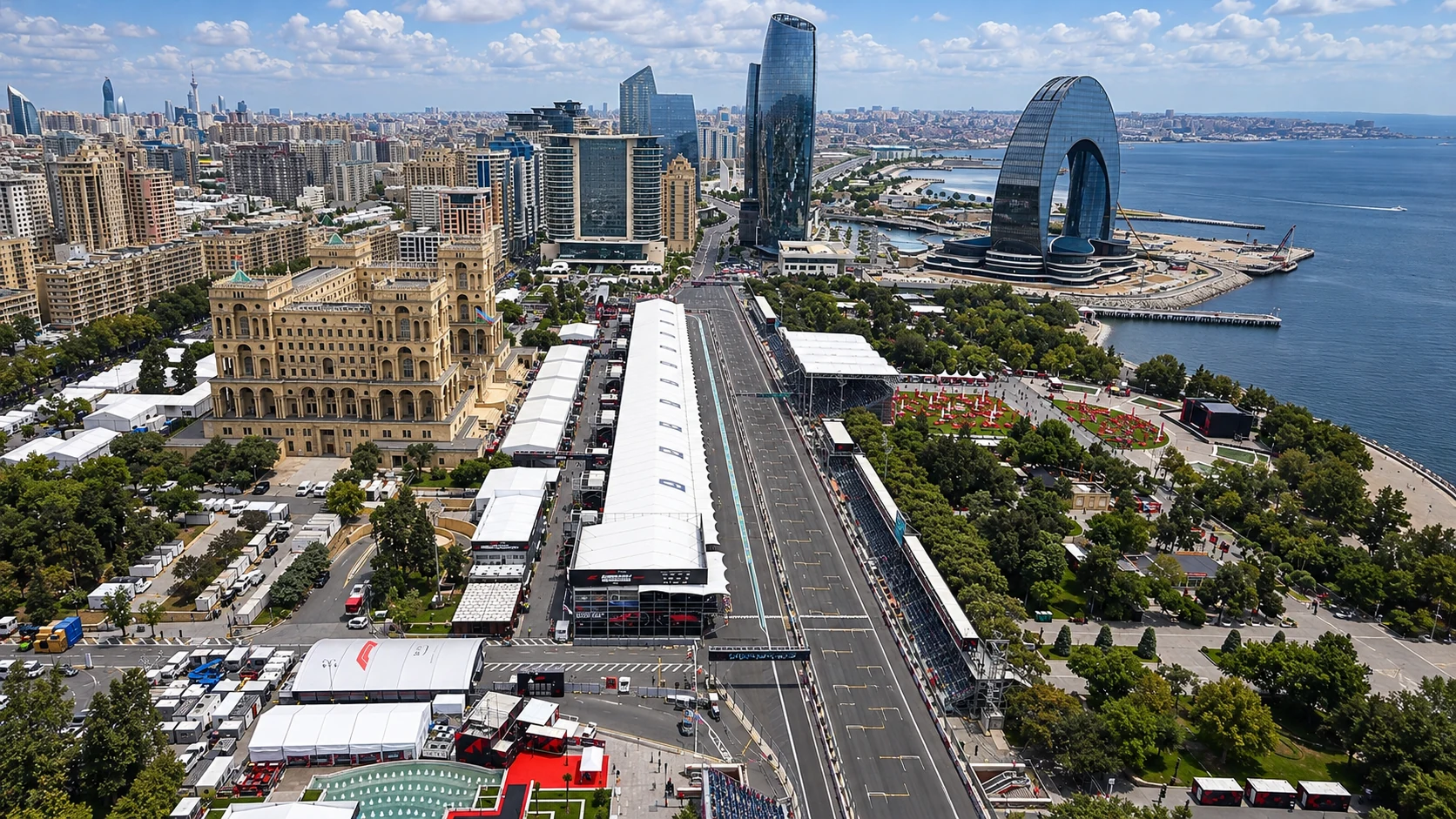 An aerial view along Baku City Circuit’s pit straight, with Government House, the white paddock roof and the Caspian waterfront.
