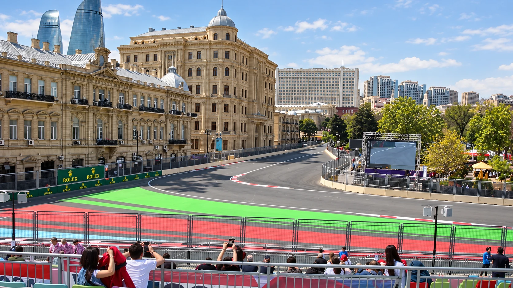 The Azneft Square corner at Baku City Circuit, with pale stone buildings and the Flame Towers beyond.