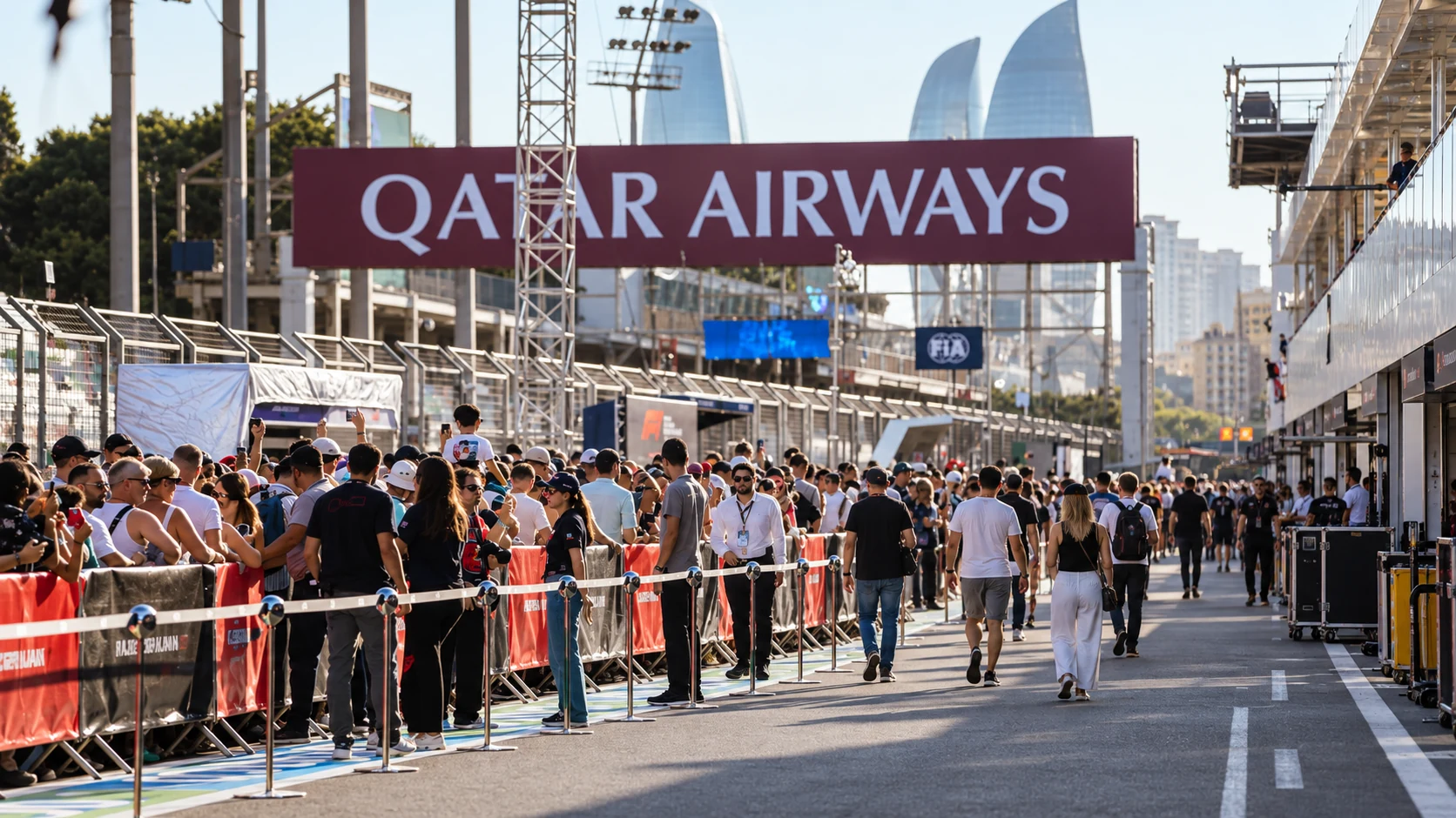 Visitors walk beside the pit garages beneath the Qatar Airways gantry at Baku City Circuit.