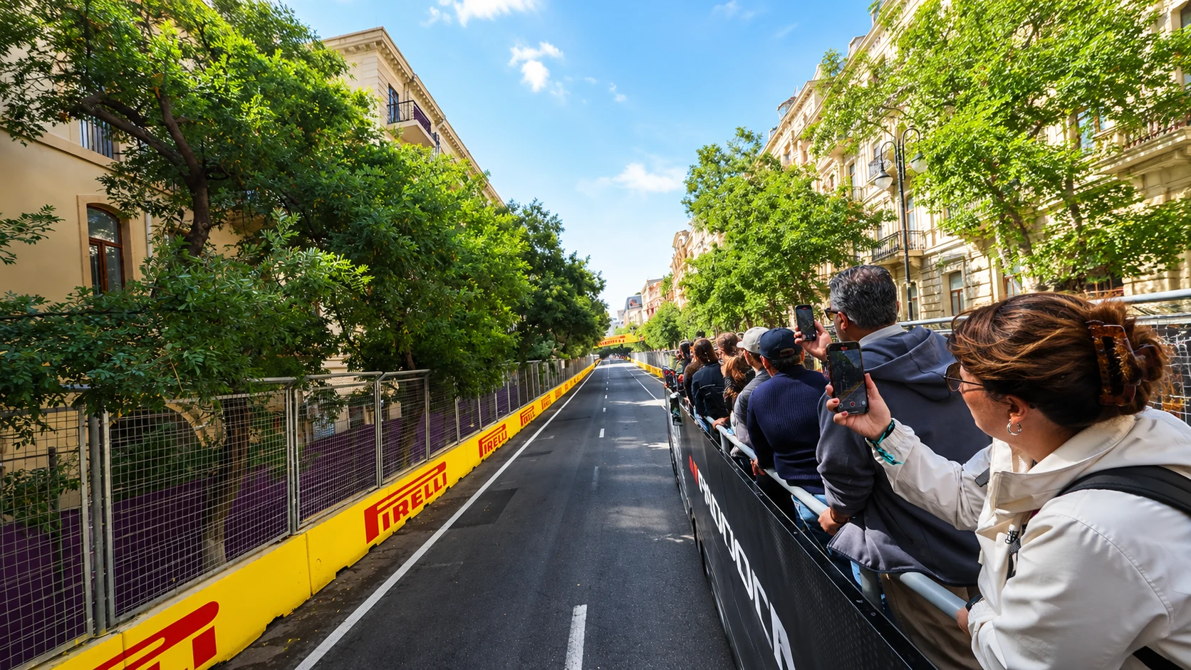 Visitors on a track tour follow a tree-lined straight between Baku’s city buildings and race barriers.