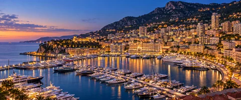 Destination artwork of Monaco: Port Hercule and Monte Carlo hillside at blue hour, marina yachts, warm lights and steep densely built Mediterranean slopes.