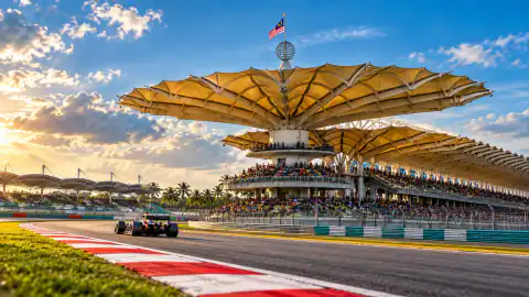 Sepang’s umbrella canopy grandstand beside the circuit in golden afternoon light.