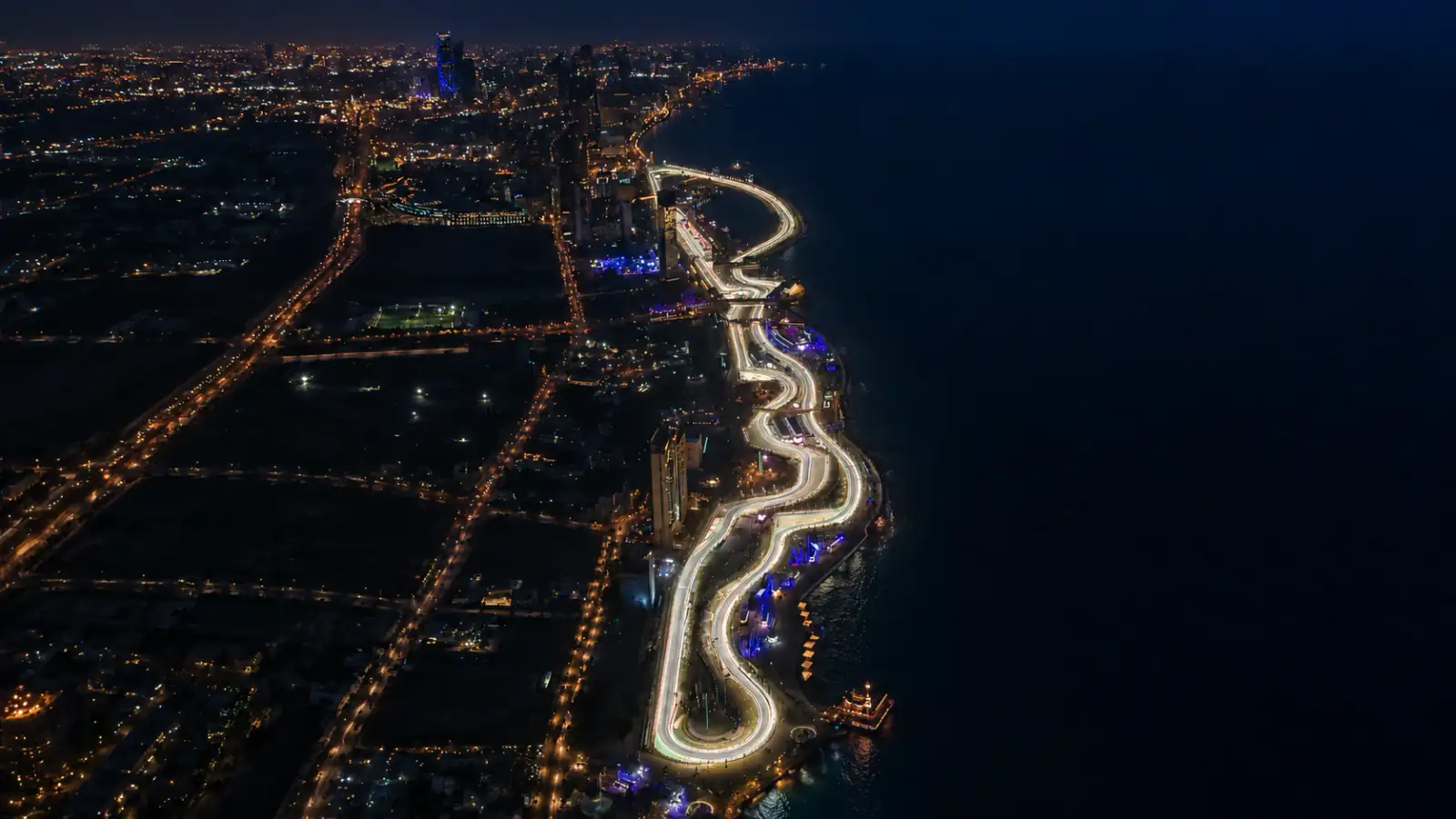 Floodlit Jeddah Corniche Circuit beside the Red Sea at blue hour