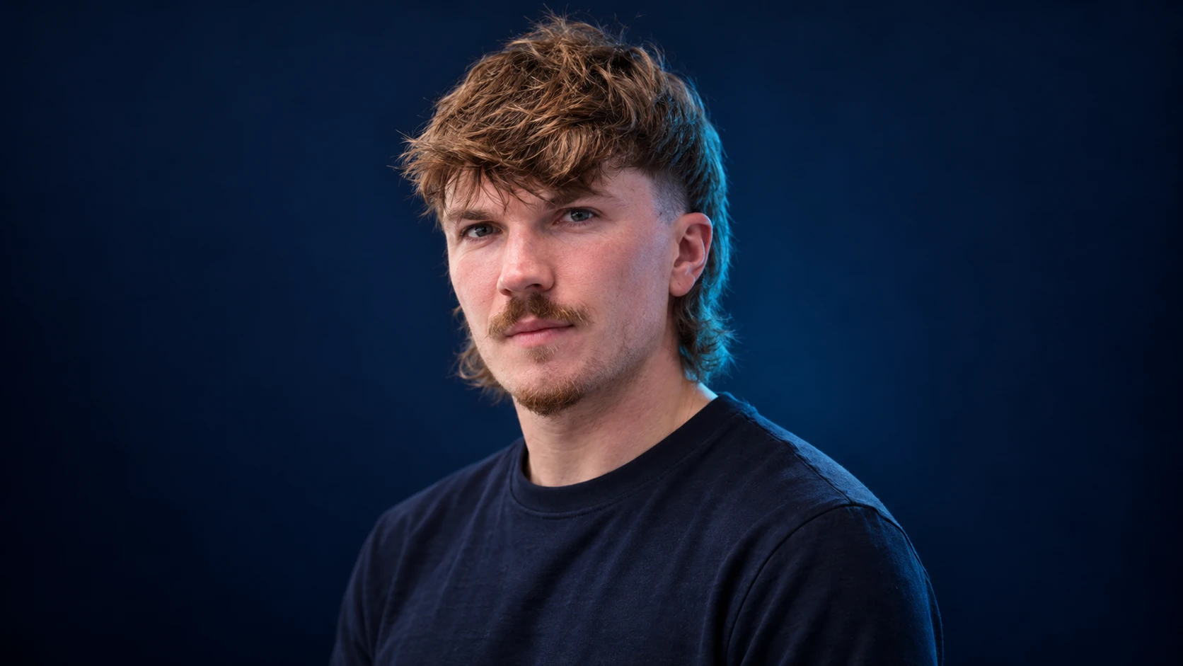 Dan Ticktum in a navy shirt against a dark background.