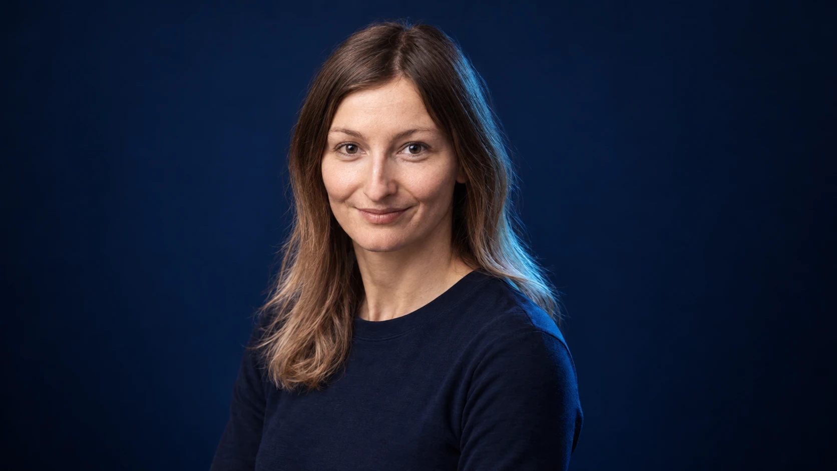 Doriane Pin in a navy shirt against a dark background.