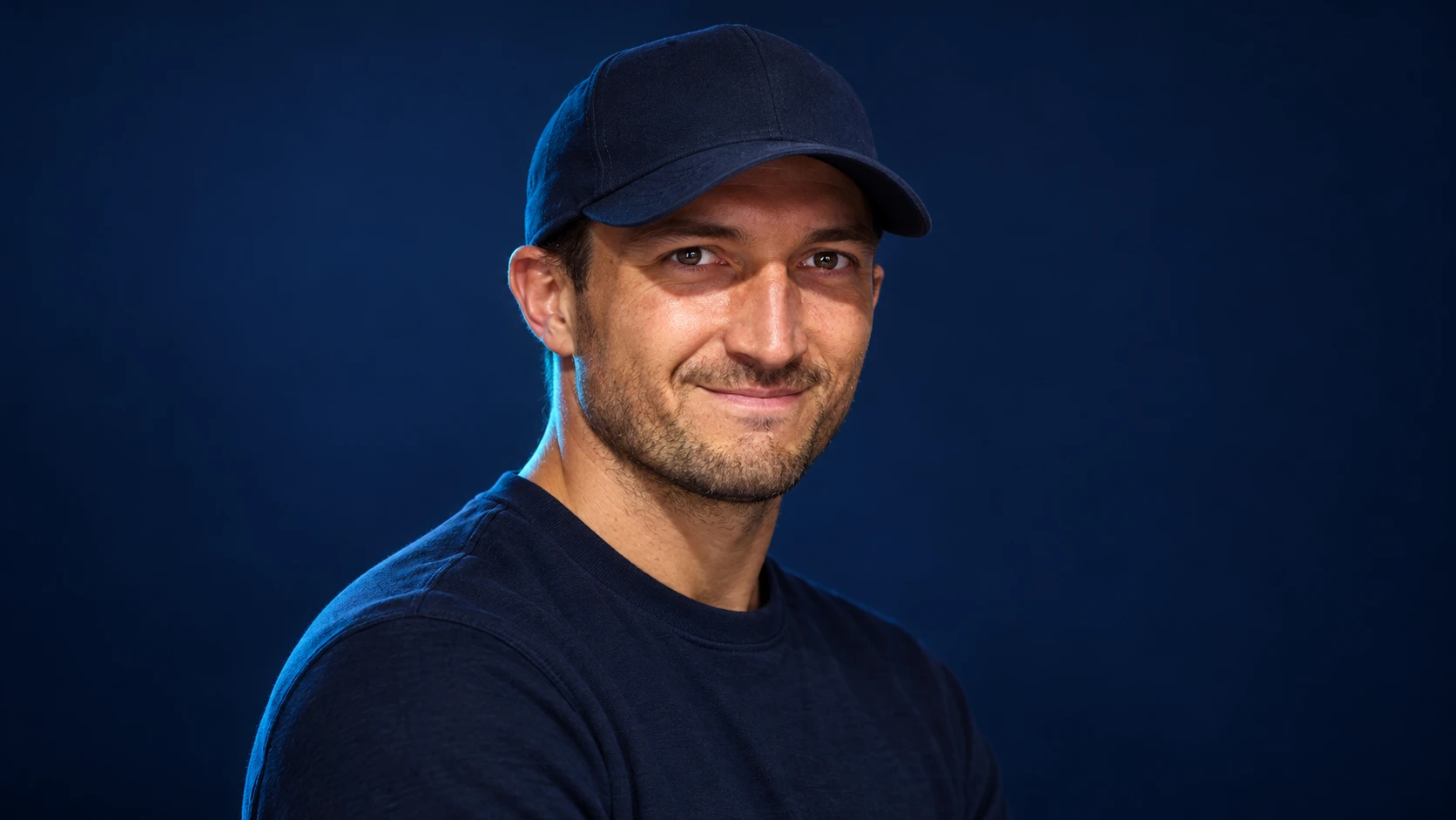 Jake Dennis in a navy shirt against a dark background.
