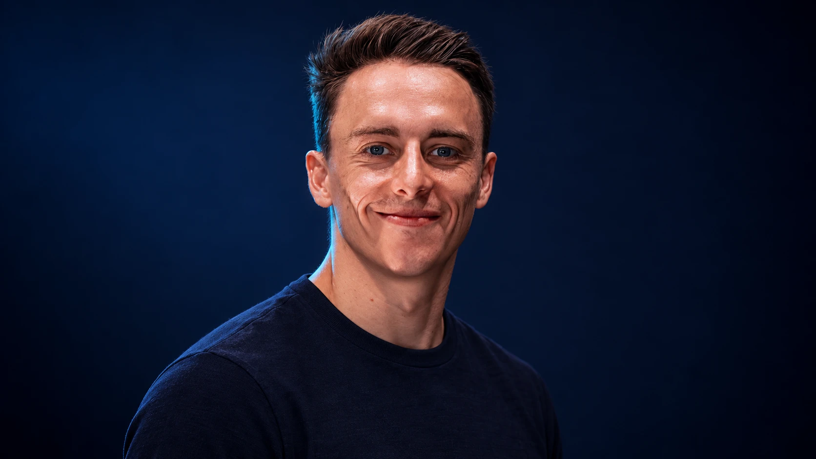 Jake Hughes in a navy shirt against a dark background.