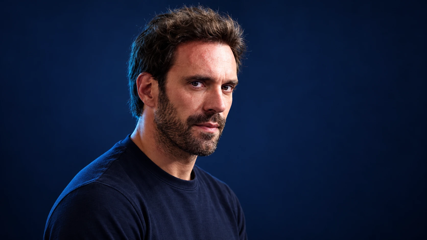 Jean-Éric Vergne in a navy shirt against a dark background.