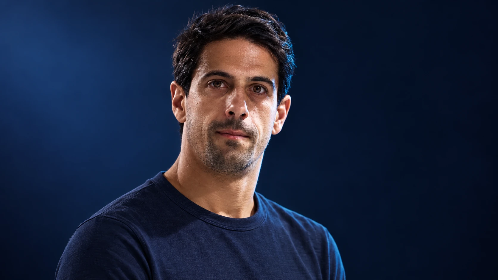 Lucas di Grassi in a navy shirt against a dark background.