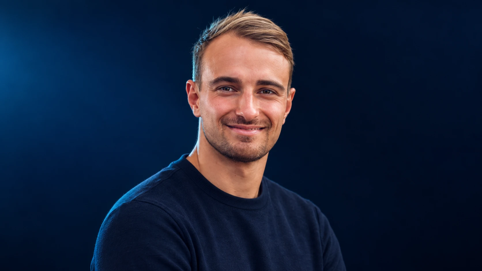 Nico Müller in a navy shirt against a dark background.