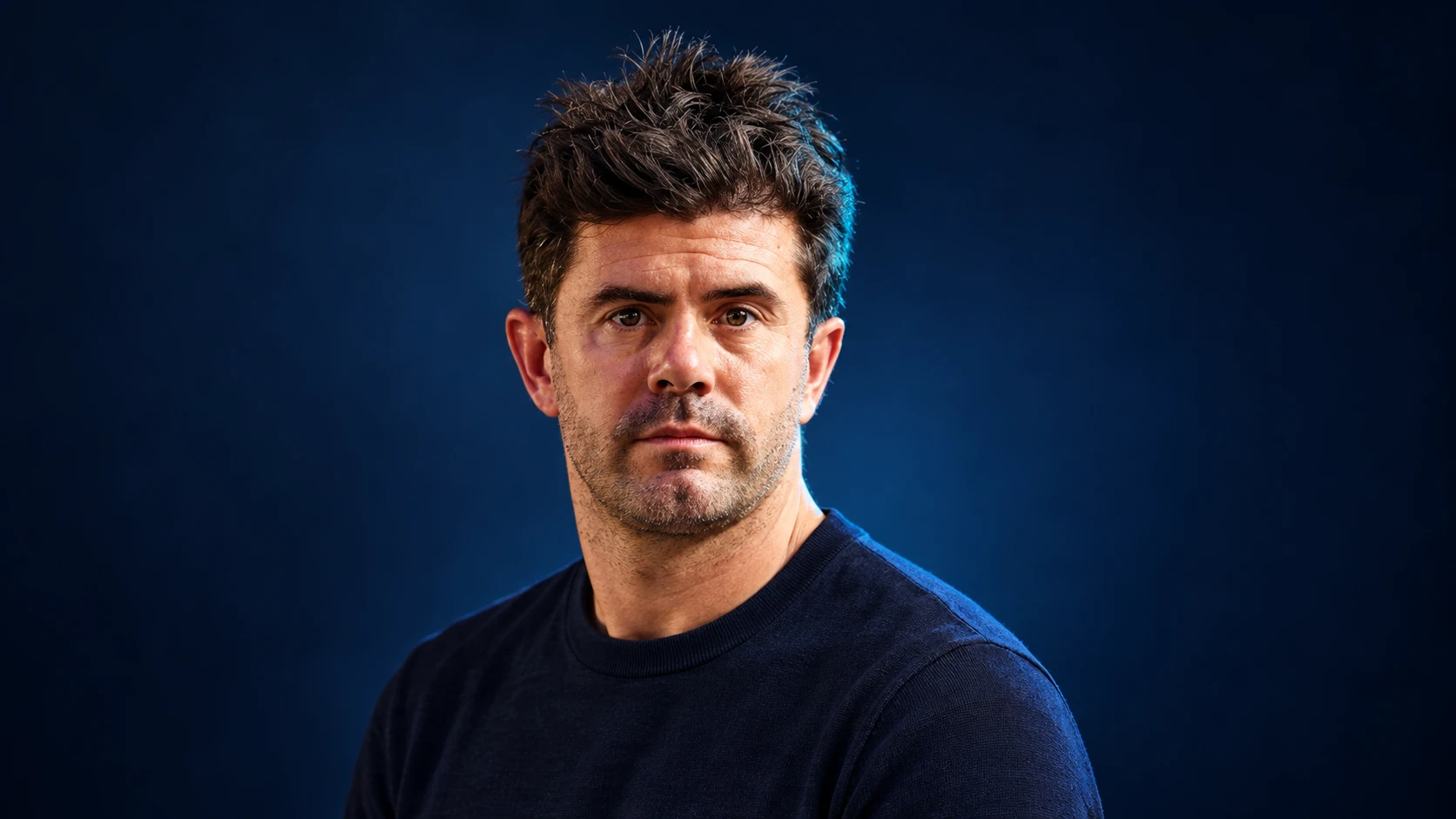 Norman Nato in a navy shirt against a dark background.