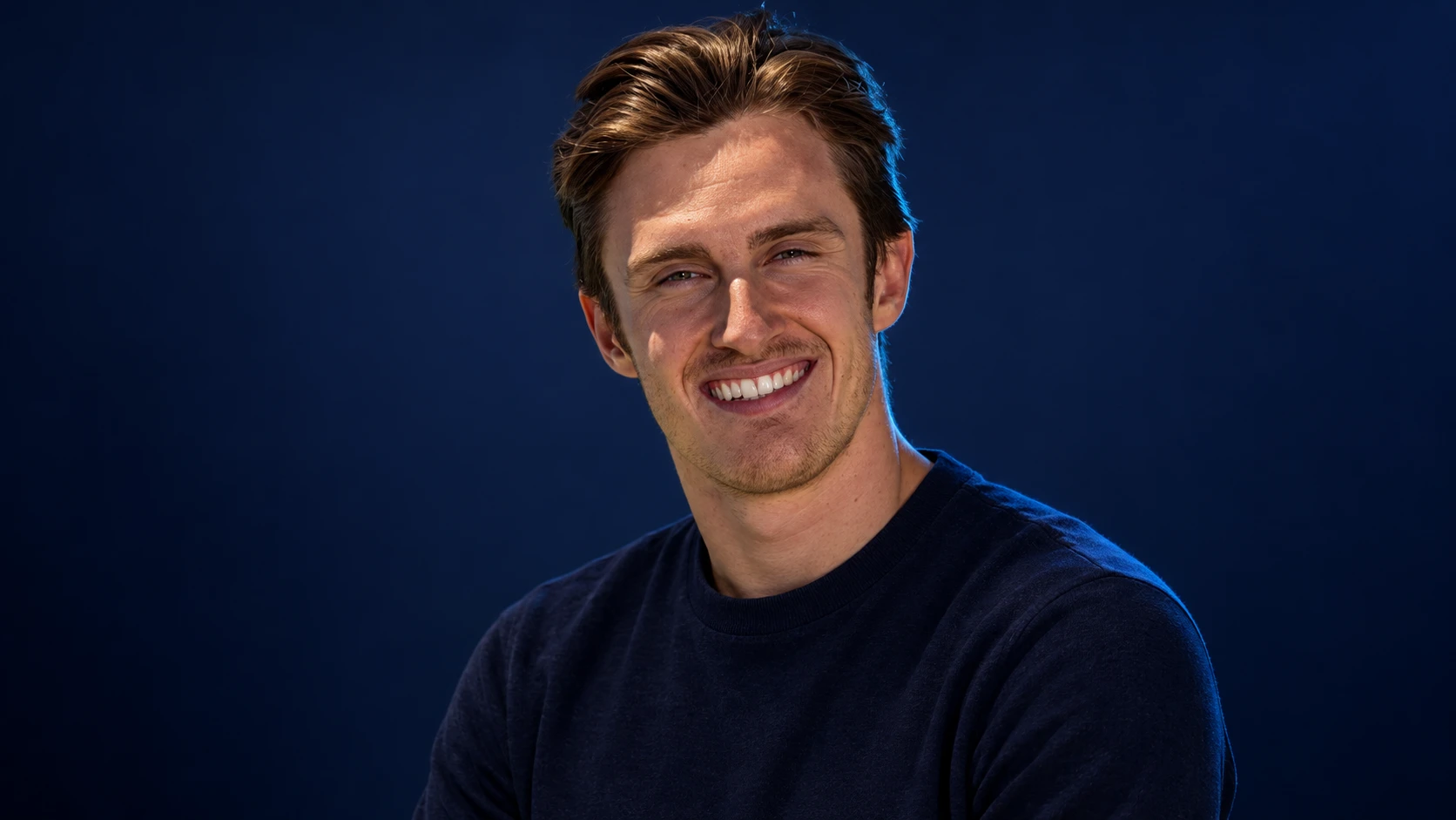 Théo Pourchaire in a navy shirt against a dark background.