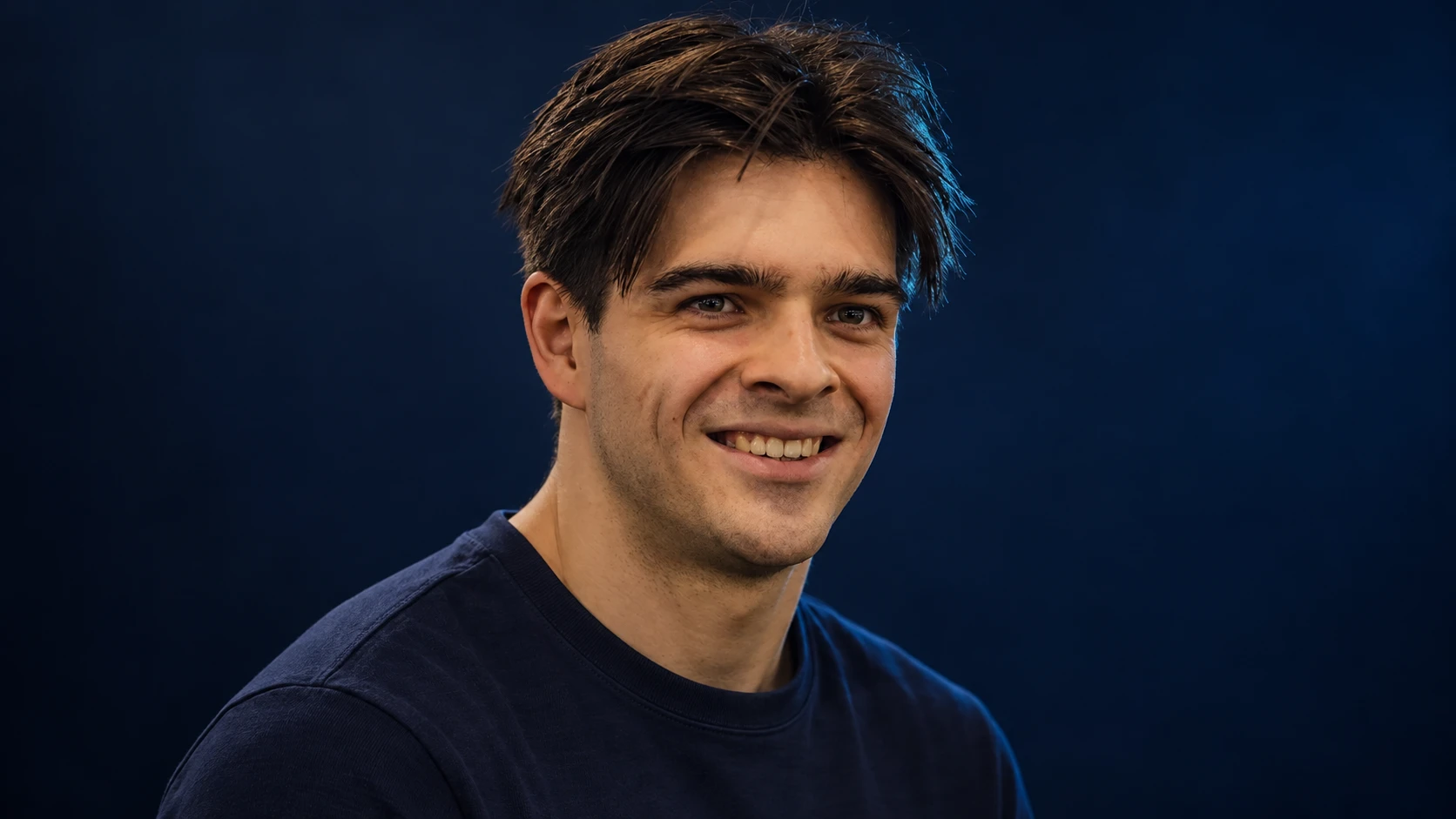 Zak O’Sullivan in a navy shirt against a dark background.