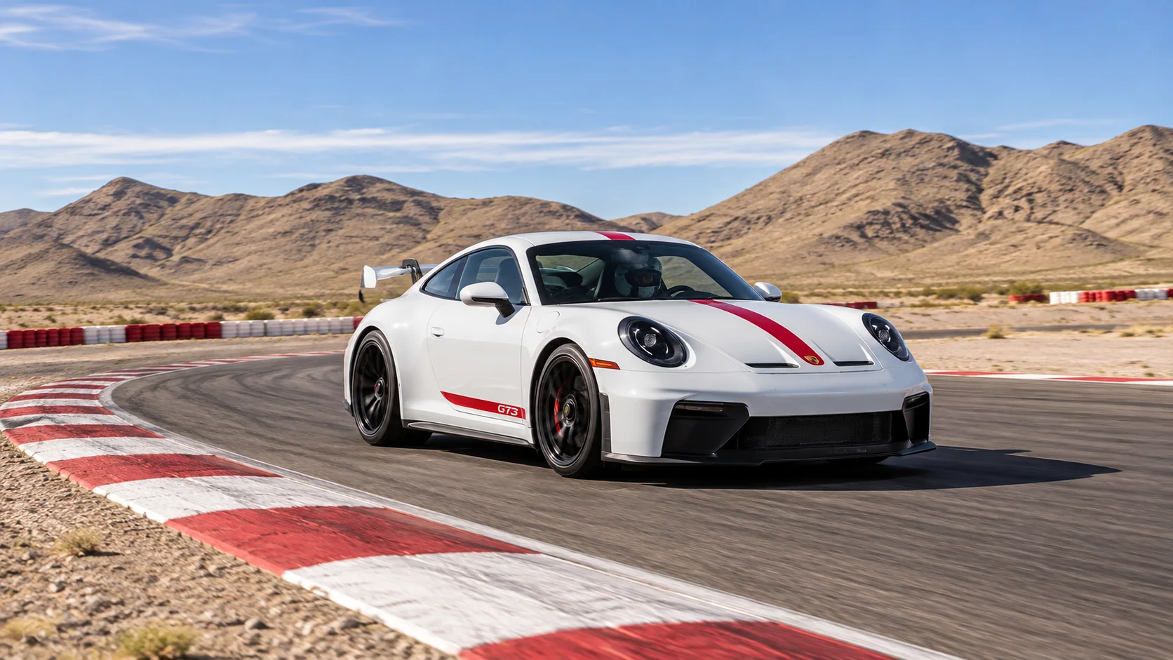 A white Porsche GT3 with red centre stripe cornering on the Exotics Racing circuit