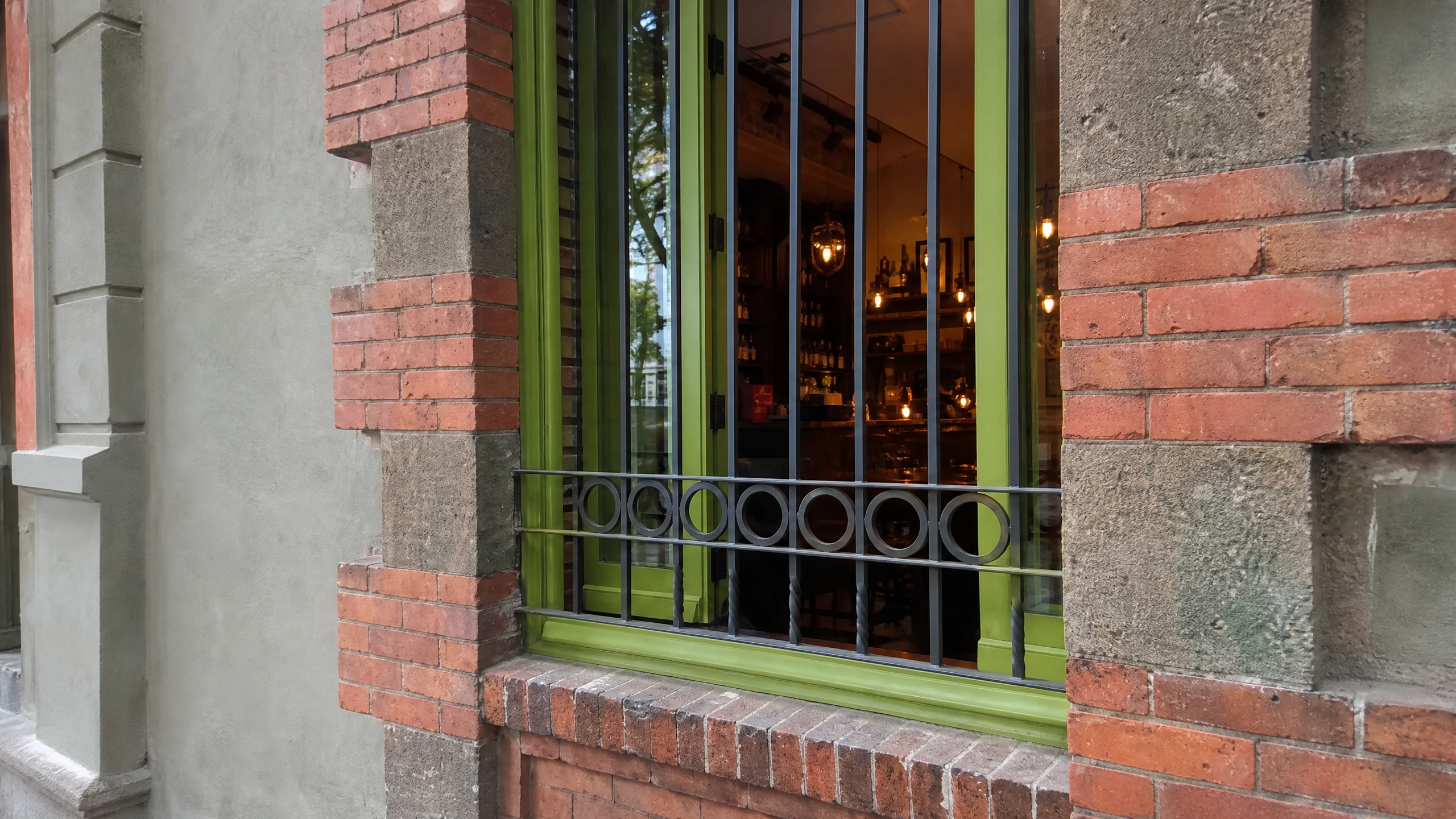 Green metal window framing and red brickwork on Café Nin’s Havre frontage