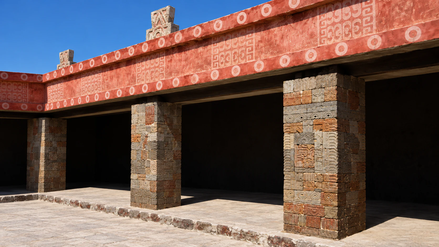 Carved stone piers and a red frieze in a Teotihuacán courtyard