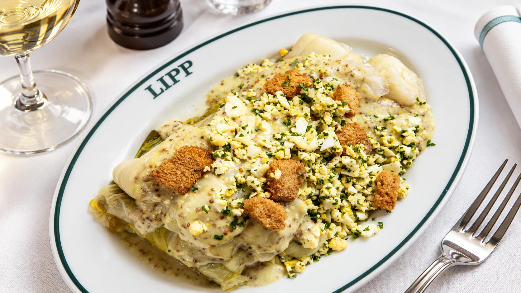 Poireaux vinaigrette: tender leeks topped with finely chopped egg, herbs and croutons on a Lipp platter.
