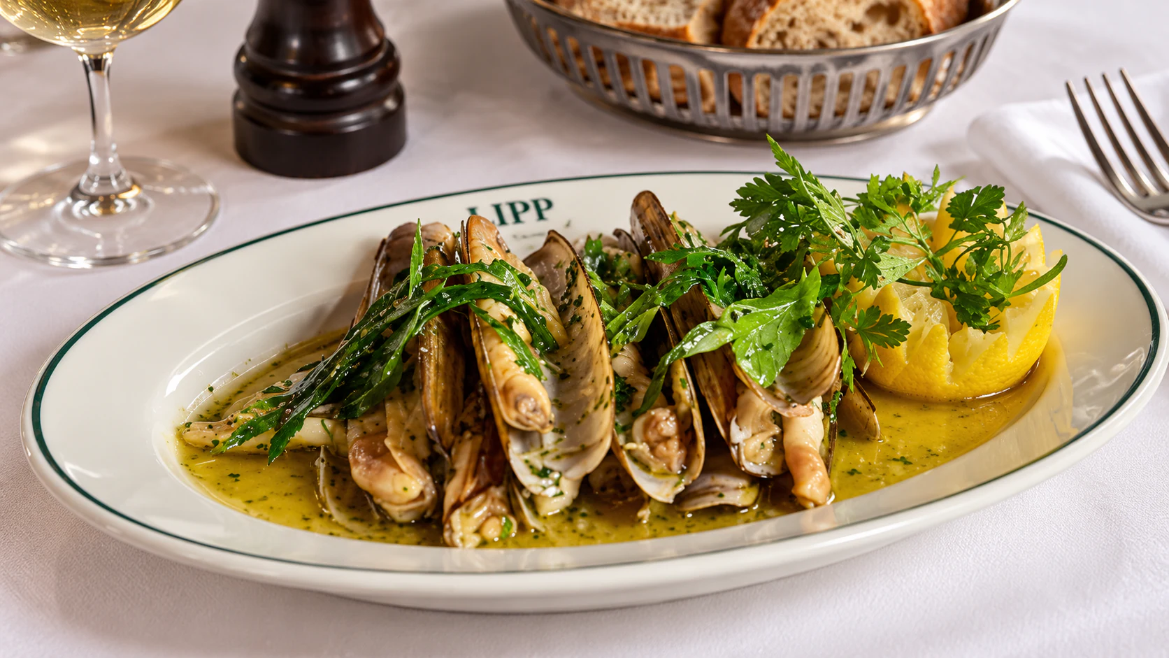 Razor clams cooked on the plancha with persillade, served in their open shells with lemon.