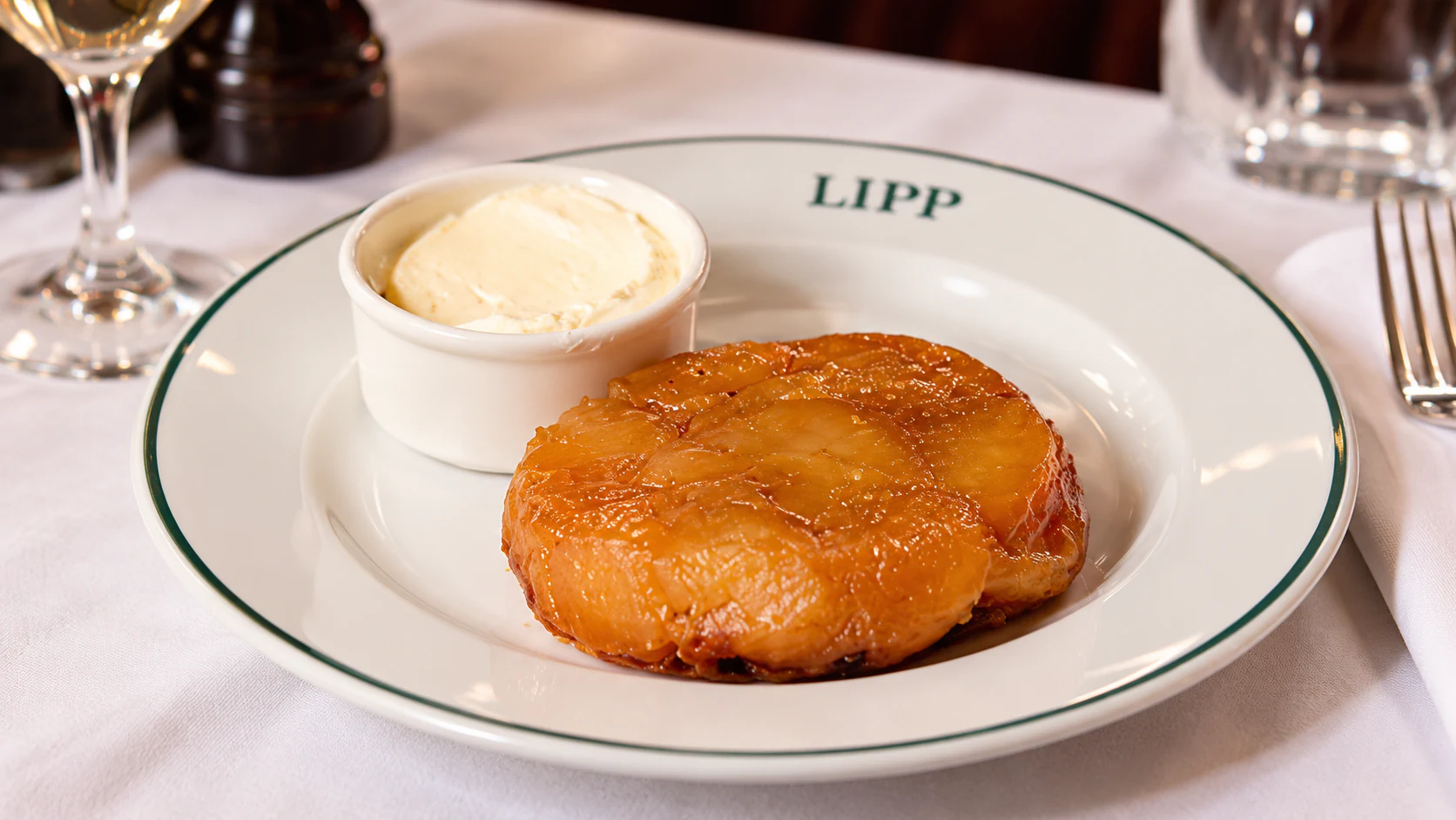 Tarte Tatin, with caramelised apples on a round pastry base and cream served alongside.