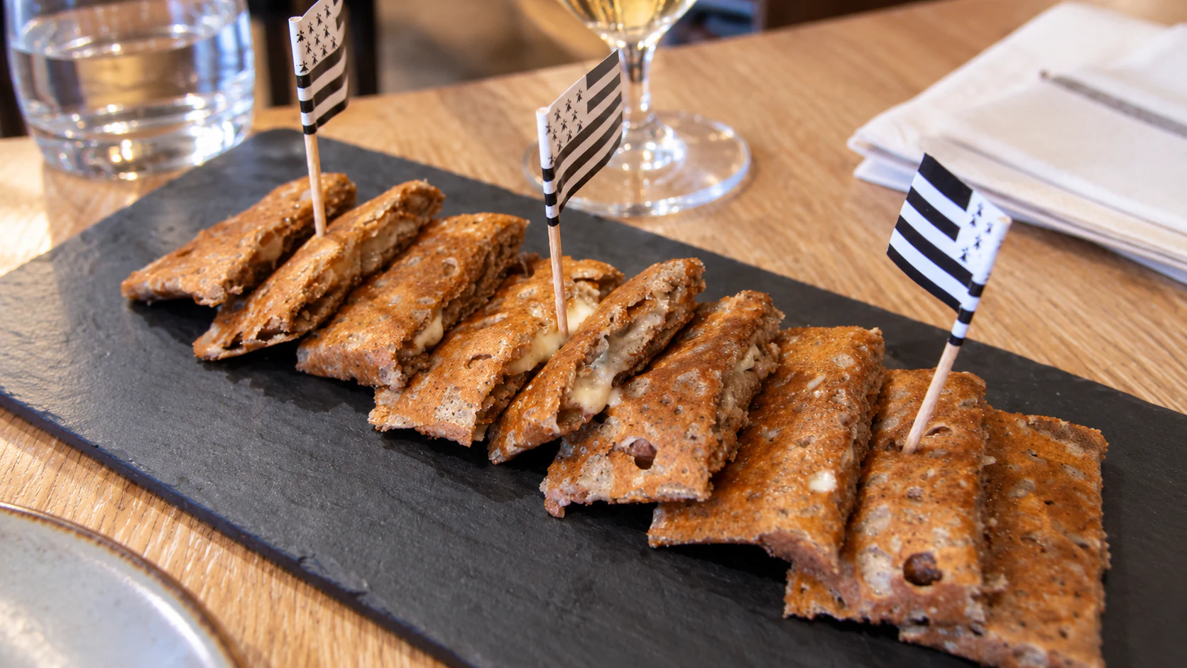 Amuse-galettes: small folded buckwheat bites arranged on a slate board for an apéritif at Breizh Café.