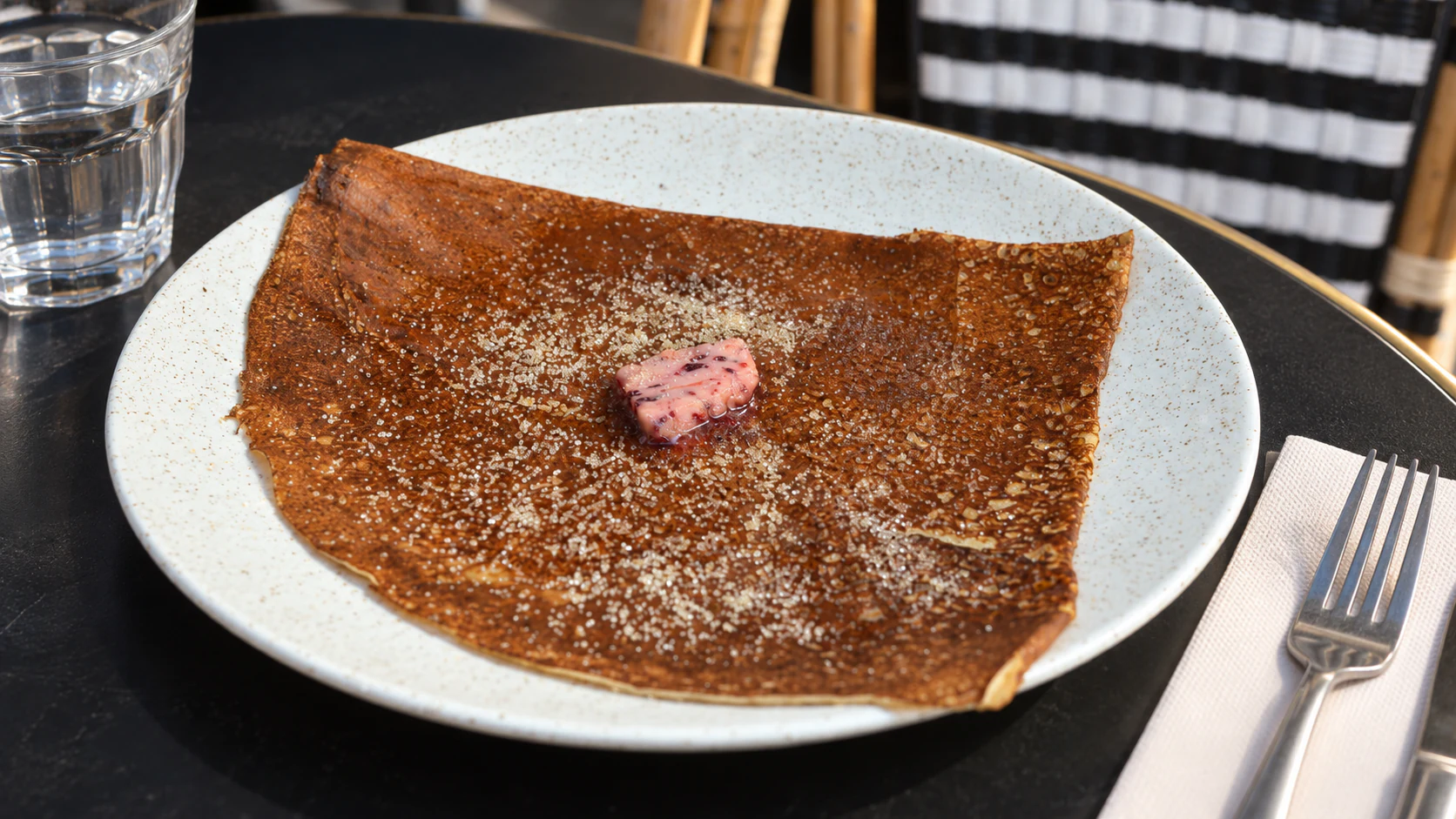A square-folded crêpe with raspberry churned butter and sugar, as served at Breizh Café Odéon.
