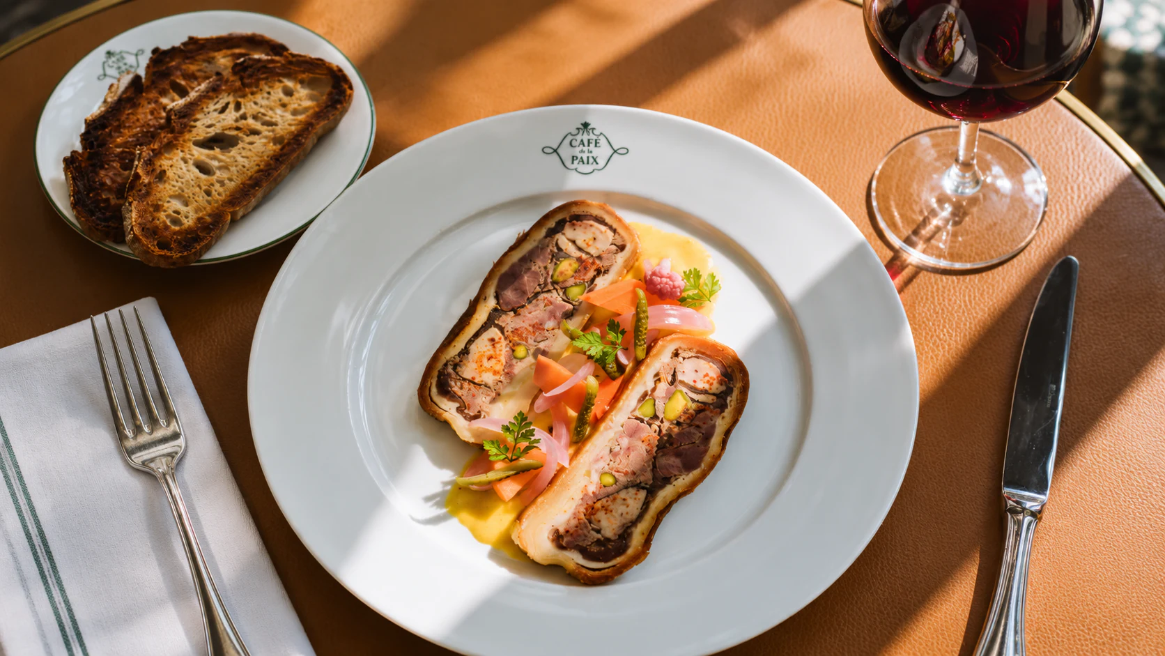 Duck pâté en croûte with a browned pastry crust and toast served alongside at Café de la Paix.