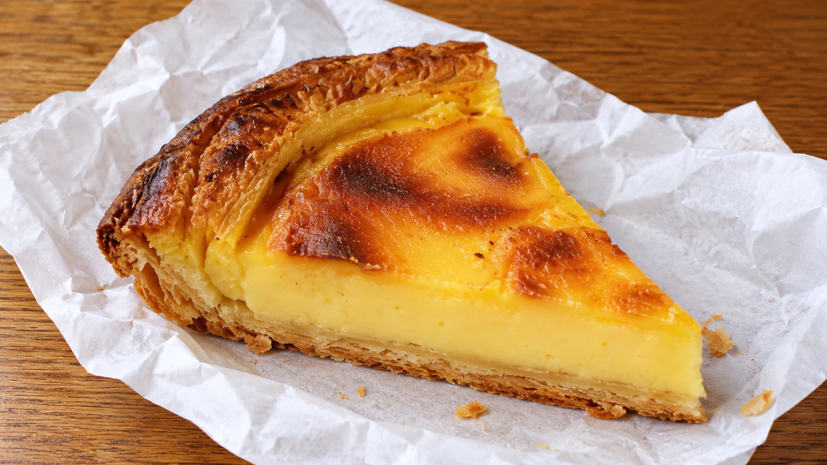 A slice of flan boulanger, with a browned custard top, pale filling and pastry base, from Du Pain et des Idées.