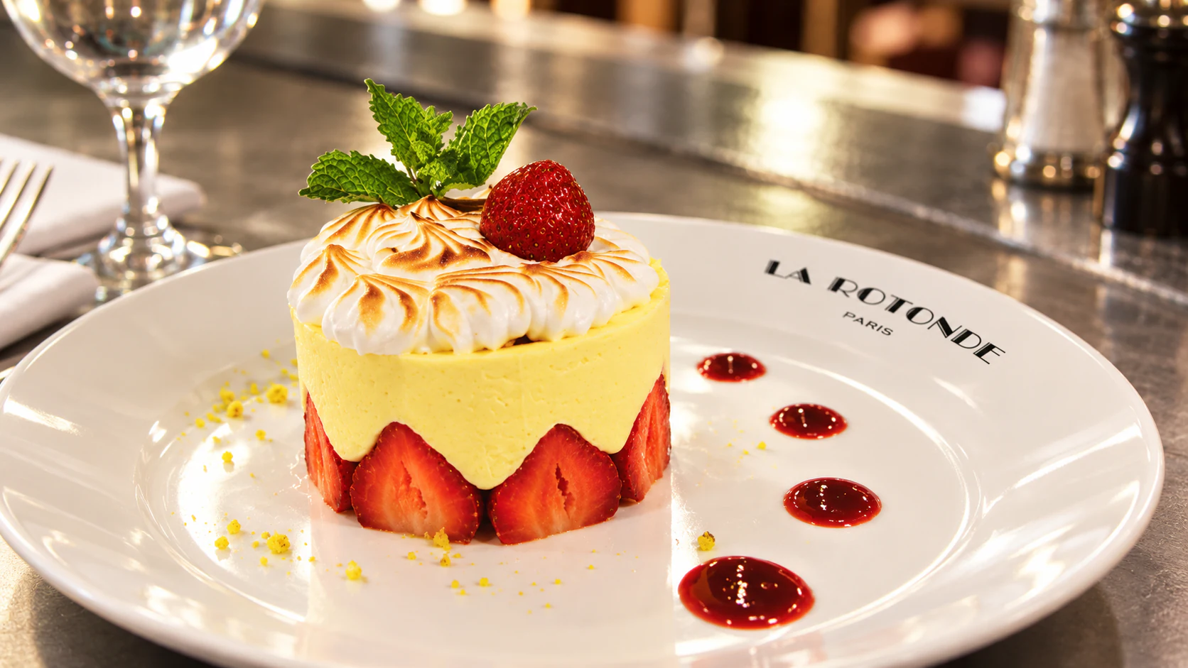 Fraisier with visible strawberry halves, a piped top and fruit coulis on a La Rotonde plate.