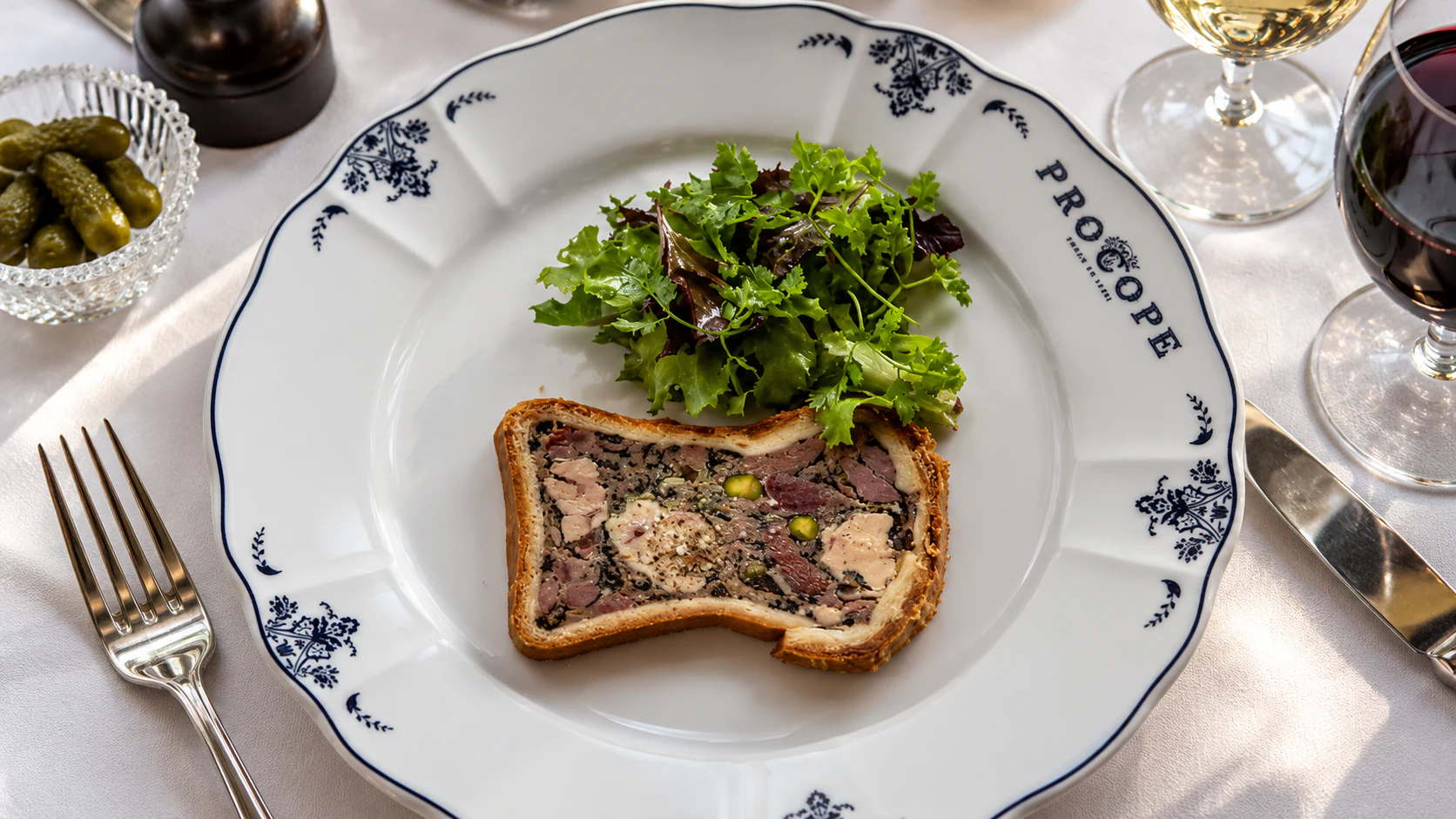 Duck pâté en croûte, sliced to show the filling inside its pastry crust, with green salad.