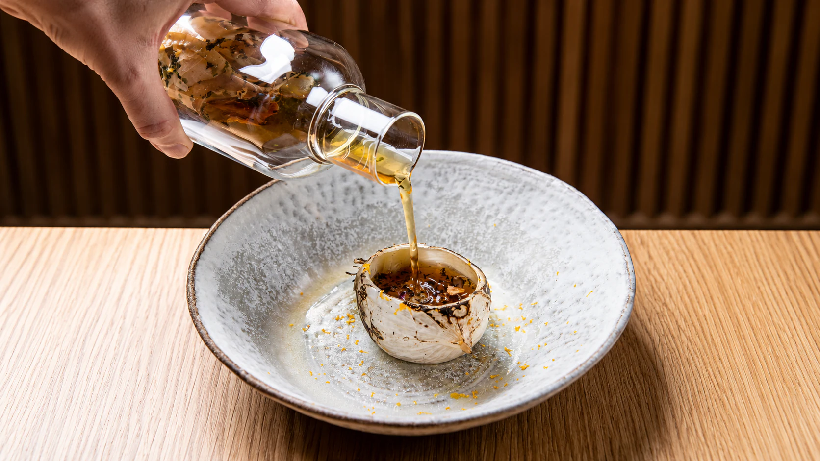 Golden consommé poured into a small ceramic cup at Astrance