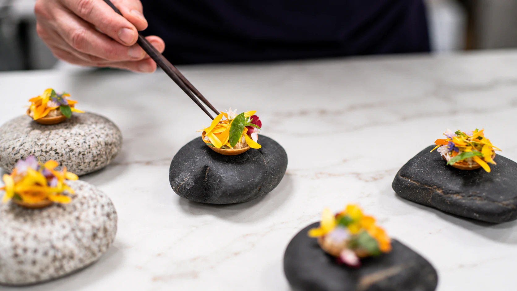 Crisp small tartlets on dark stone serving pieces at Astrance