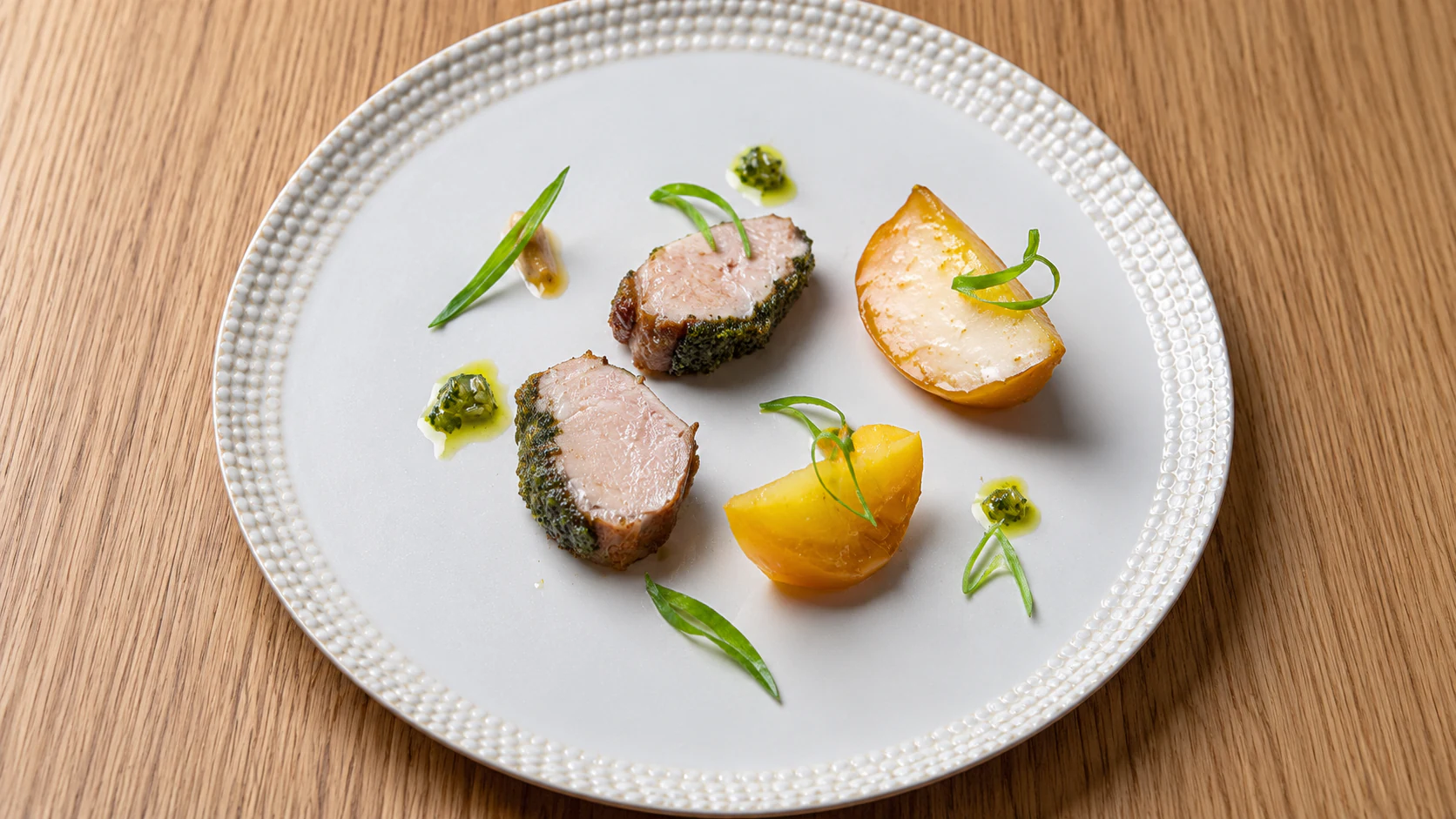 Two medallions with yellow citrus on a white plate at Astrance