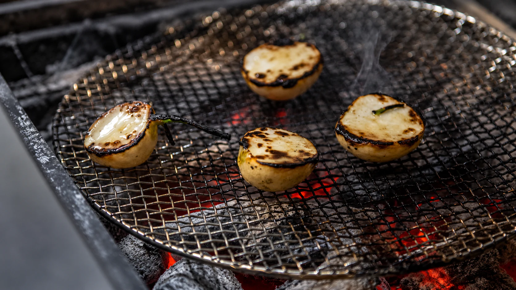 Small round vegetable pieces cooking over charcoal at Astrance