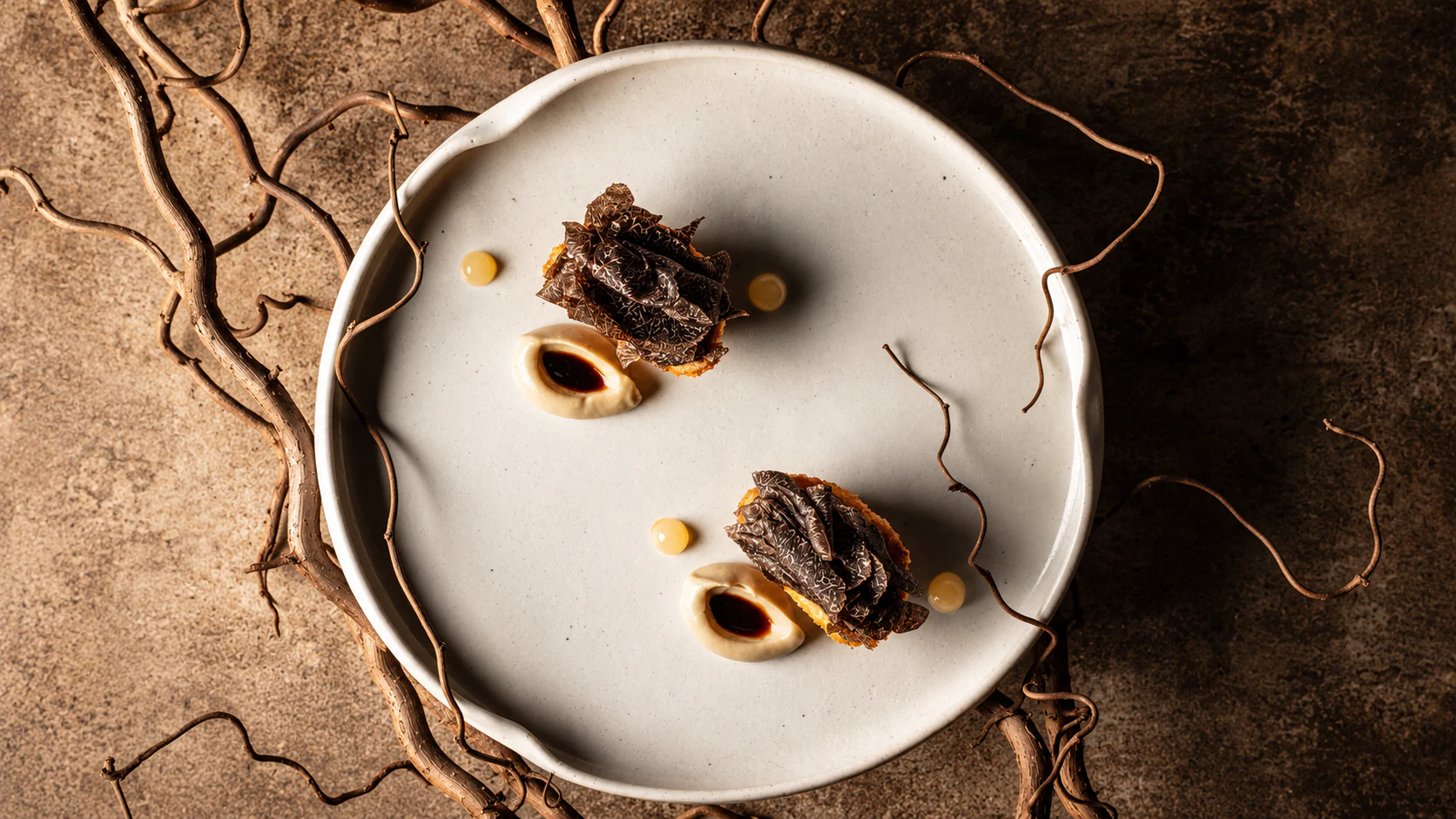 Two black-truffle tasting portions on a pale ceramic plate at David Toutain