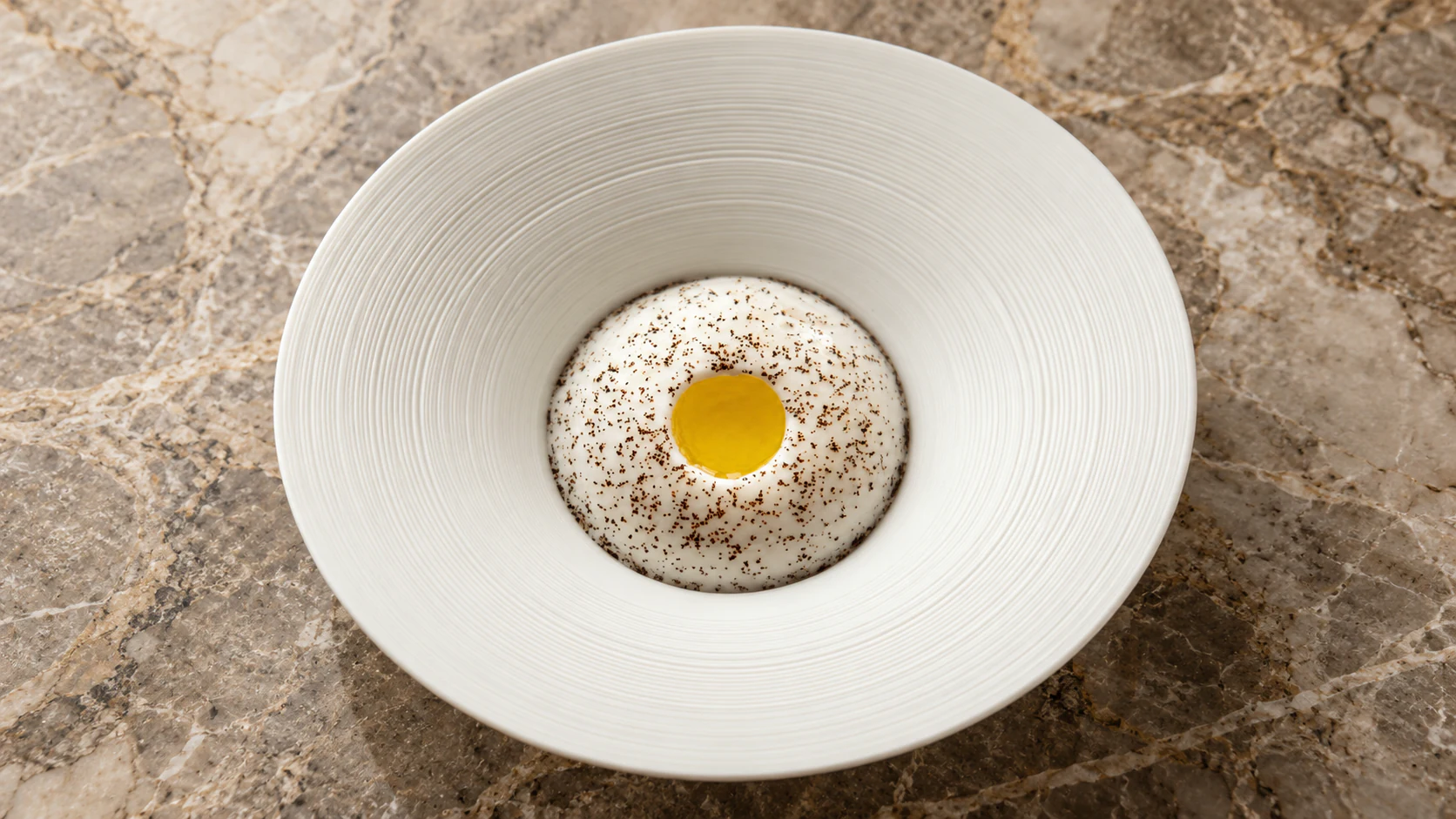 Golden centre and speckled foam in a ridged bowl at Le Jules Verne