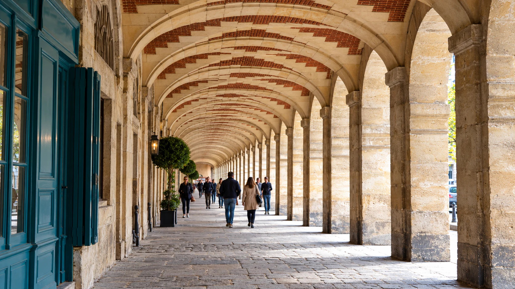Brick-and-stone vaults and stone pillars along the covered arcade at Place des Vosges